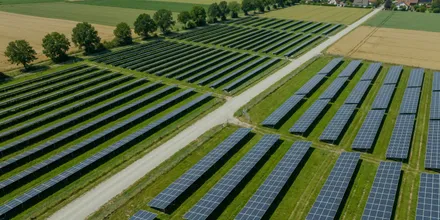Luftbild zweier benachbarter Solarparks, getrennt durch einen Feldweg, dahinter ein Dorf