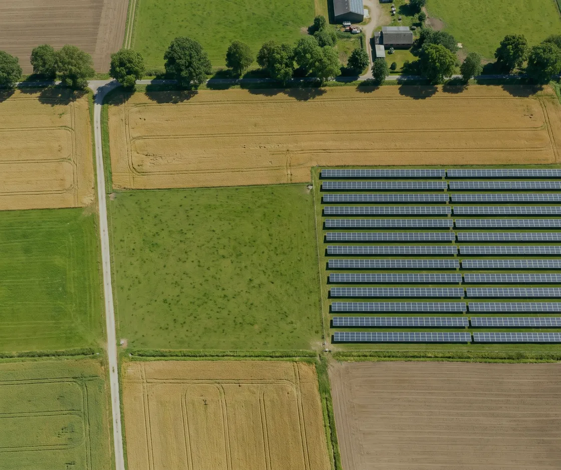 Senkrechtes Luftbild einer Feldflur, in der eine einzelne Solaranlage wie eine Parzelle zwischen den Ackerschlägen liegt