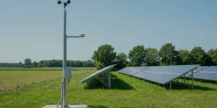 Messmast mit Windschalen und Sensor am Rand einer Solaranlage